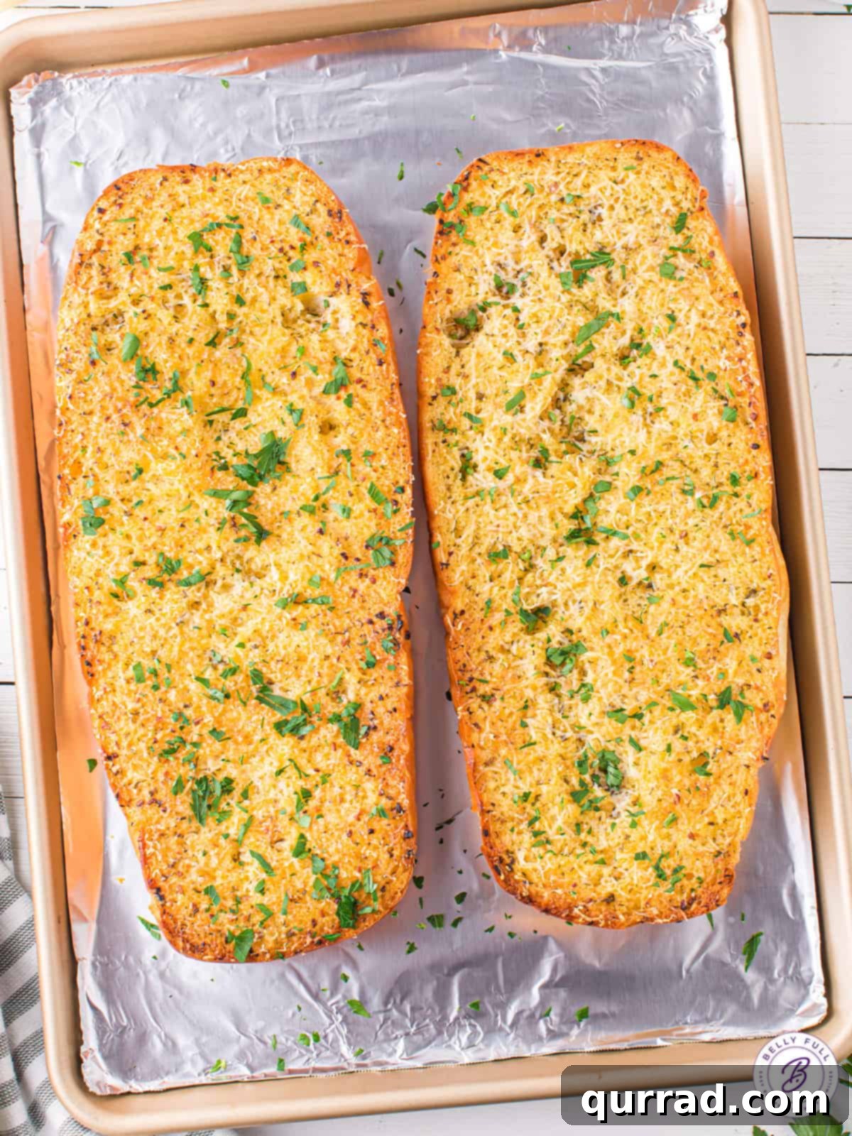 Golden Garlic Goodness 3 Two golden loaves of freshly baked homemade garlic bread resting on a baking sheet, ready to be sliced and served.
