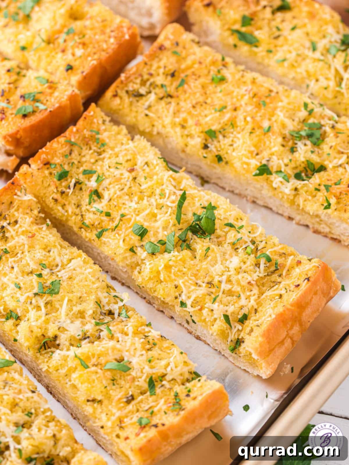 Golden Garlic Goodness 4 Perfectly sliced pieces of garlic bread, golden and toasted, arranged neatly on a baking sheet, ready for serving.