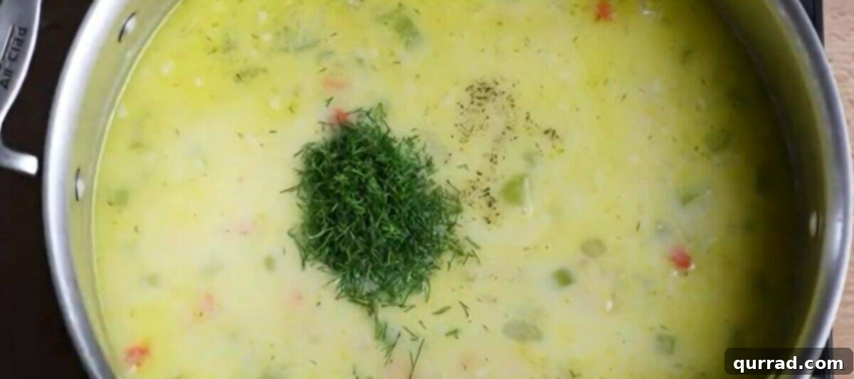 Golden Avgolemono Greek Lemon Chicken Soup 8 Fresh chopped dill being stirred into the Avgolemono soup in the saucepan.