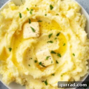 overhead bowl of creamy fluffy mashed potatoes with pats of butter