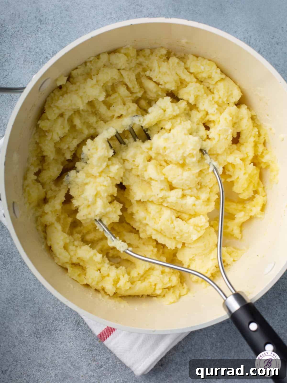 Melt-in-Your-Mouth Mashed Potatoes 4 mashed potatoes with potato masher in mixing bowl, ready to be served