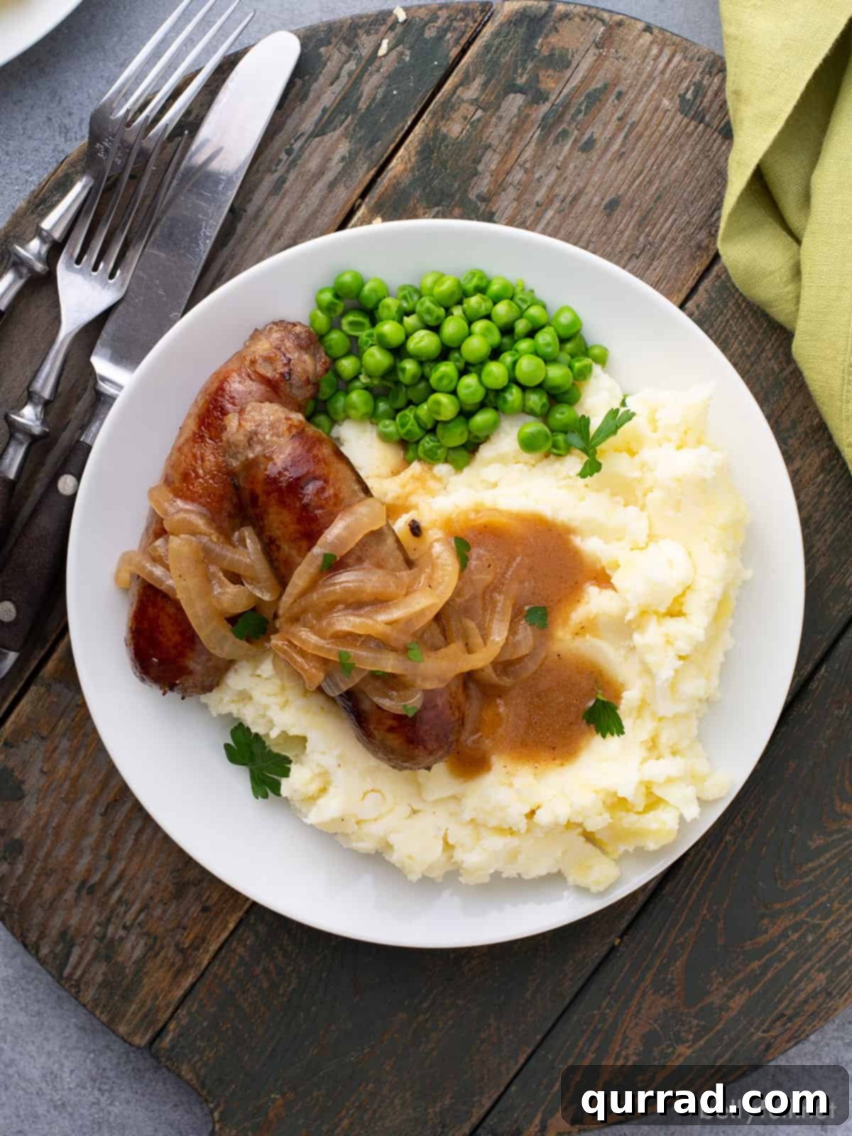 Sizzling Sausages and Creamy Mash 10 A beautifully plated serving of Bangers and Mash, showcasing the golden sausages, creamy mash, and glossy onion gravy on a wooden board.