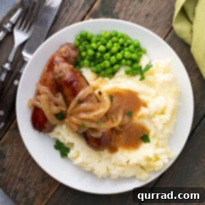 Overhead picture of Bangers and Mash with onion gravy on a wooden board.