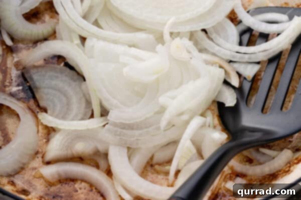 Sizzling Sausages and Creamy Mash 6 Thinly sliced onions sautéing in a skillet with melted butter, beginning to soften.