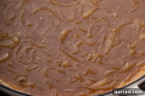 Sizzling Sausages and Creamy Mash 8 Rich onion gravy simmering in a skillet, thick and deeply colored.