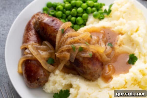 Sizzling Sausages and Creamy Mash 9 Plated Bangers and Mash, featuring sausages on creamy mashed potatoes, generously topped with onion gravy.