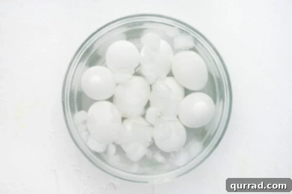 Freshly hard-boiled eggs cooling rapidly in a bowl of ice water.