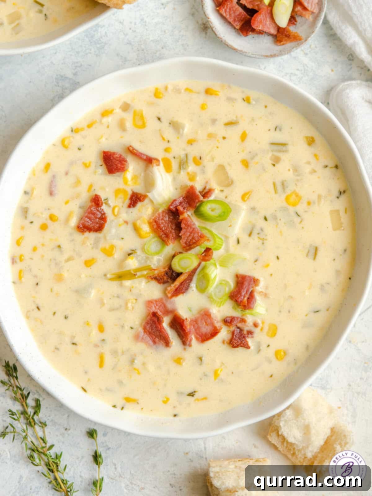 Creamy Golden Corn Chowder 2 A large bowl of creamy corn and potato soup topped with crispy bacon pieces and fresh herbs.