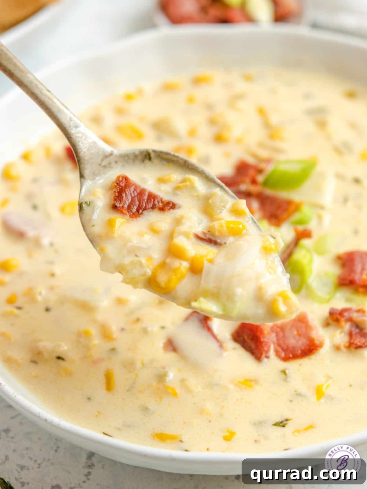 Creamy Golden Corn Chowder 11 A spoonful of rich, creamy corn chowder being served over a full bowl.