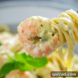 Shrimp and creamy pesto pasta swirled around fork, ready to be served.