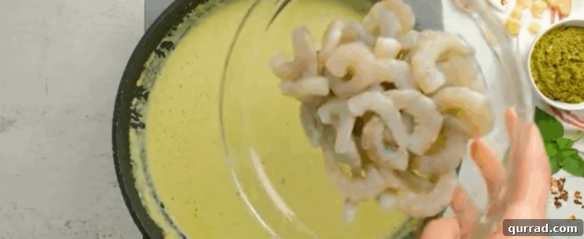 Zesty Shrimp Pesto Pasta 7 Adding pesto and shrimp to the simmering cream sauce in a skillet.