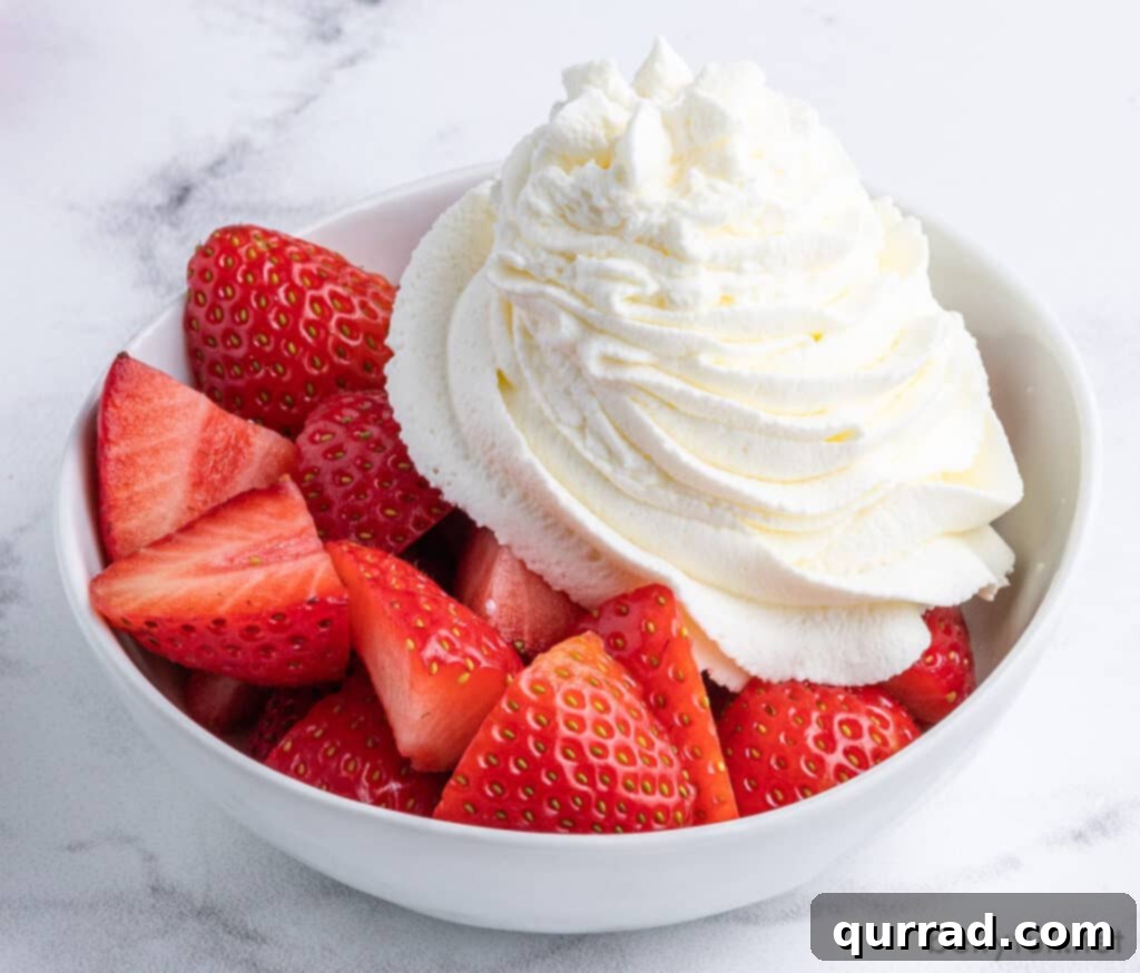 Cloud-Like Homemade Whipped Cream 5 Piped homemade whipped cream artfully arranged on a bed of fresh, sliced strawberries, a perfect dessert topping.