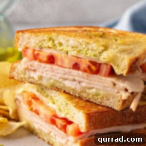 Elevate Your Grilled Cheese Game 6 pesto grilled cheese sandwich cut in half and stacked on plate