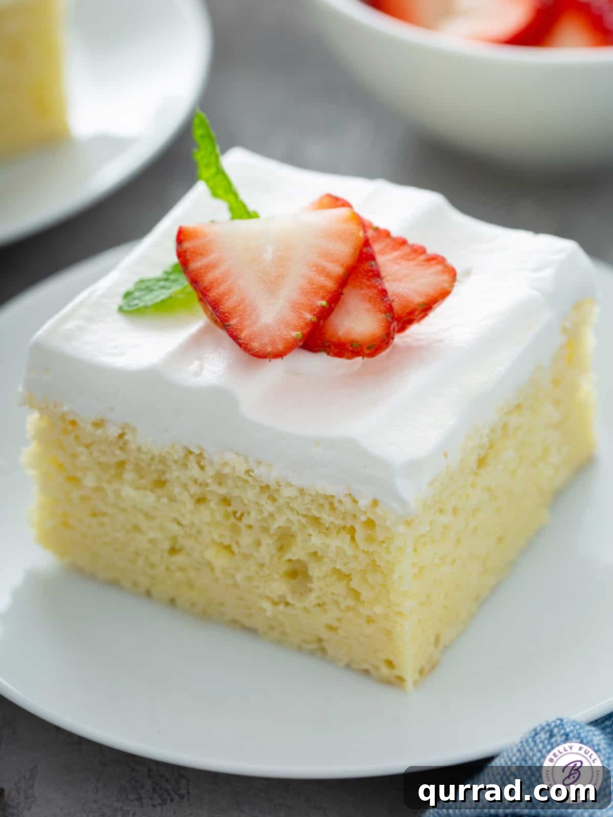 Super Moist Three Milk Cake 2 A delectable slice of Tres Leches cake adorned with fresh, vibrant sliced strawberries, ready to be enjoyed.