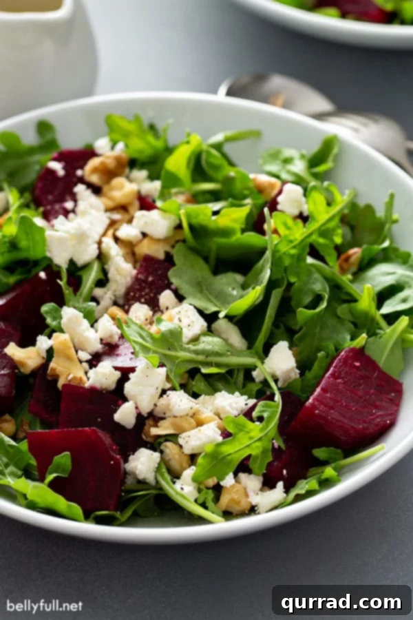 Close-up side view of Arugula Beet Salad showcasing layers of arugula, roasted beets, feta cheese, and walnuts
