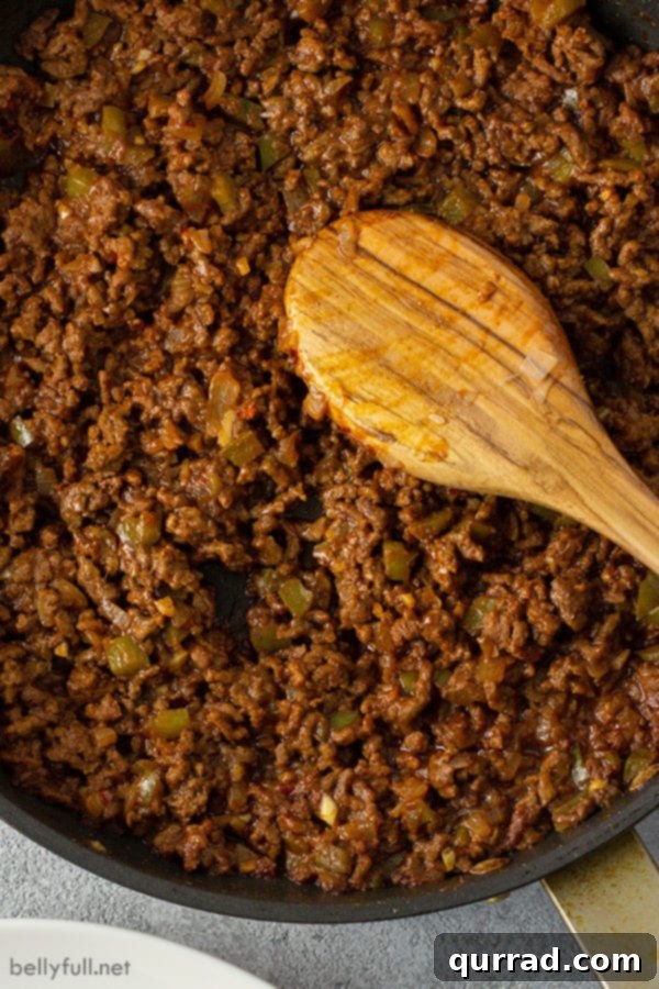 overhead of sloppy joe meat in skillet with wooden spoon