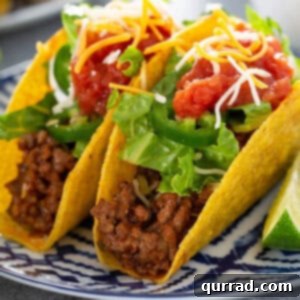 2 crispy tacos on ornate plate topped with lettuce and salsa