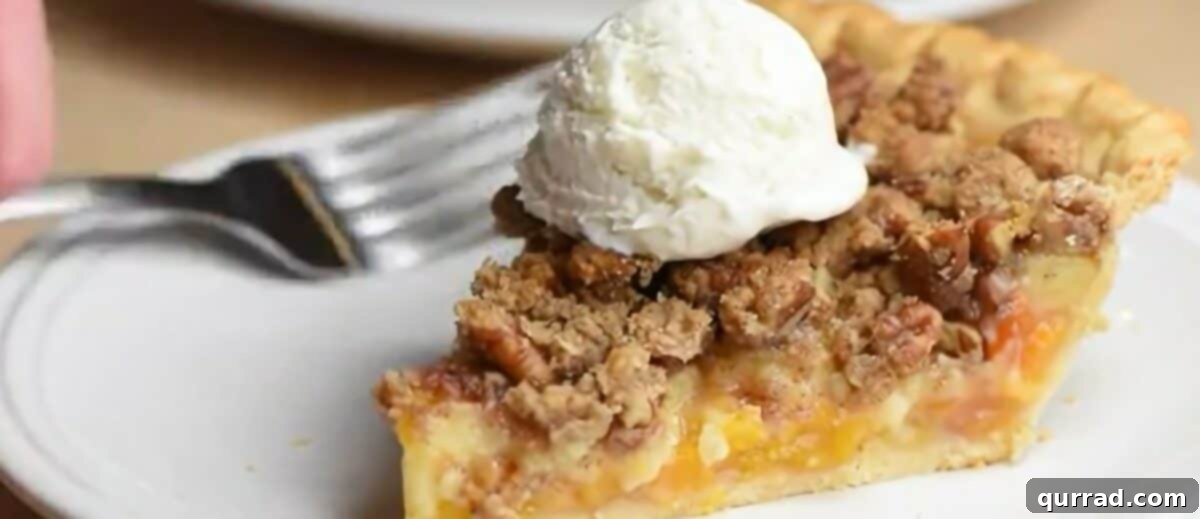 Velvet Peach Pecan Pie 7 A slice of peach pie with a scoop of vanilla ice cream on top on a plate with a fork.
