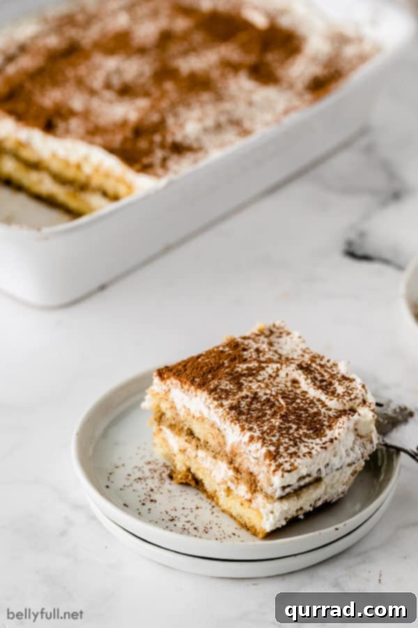 Tiramisu on a white plate with casserole dish in background.