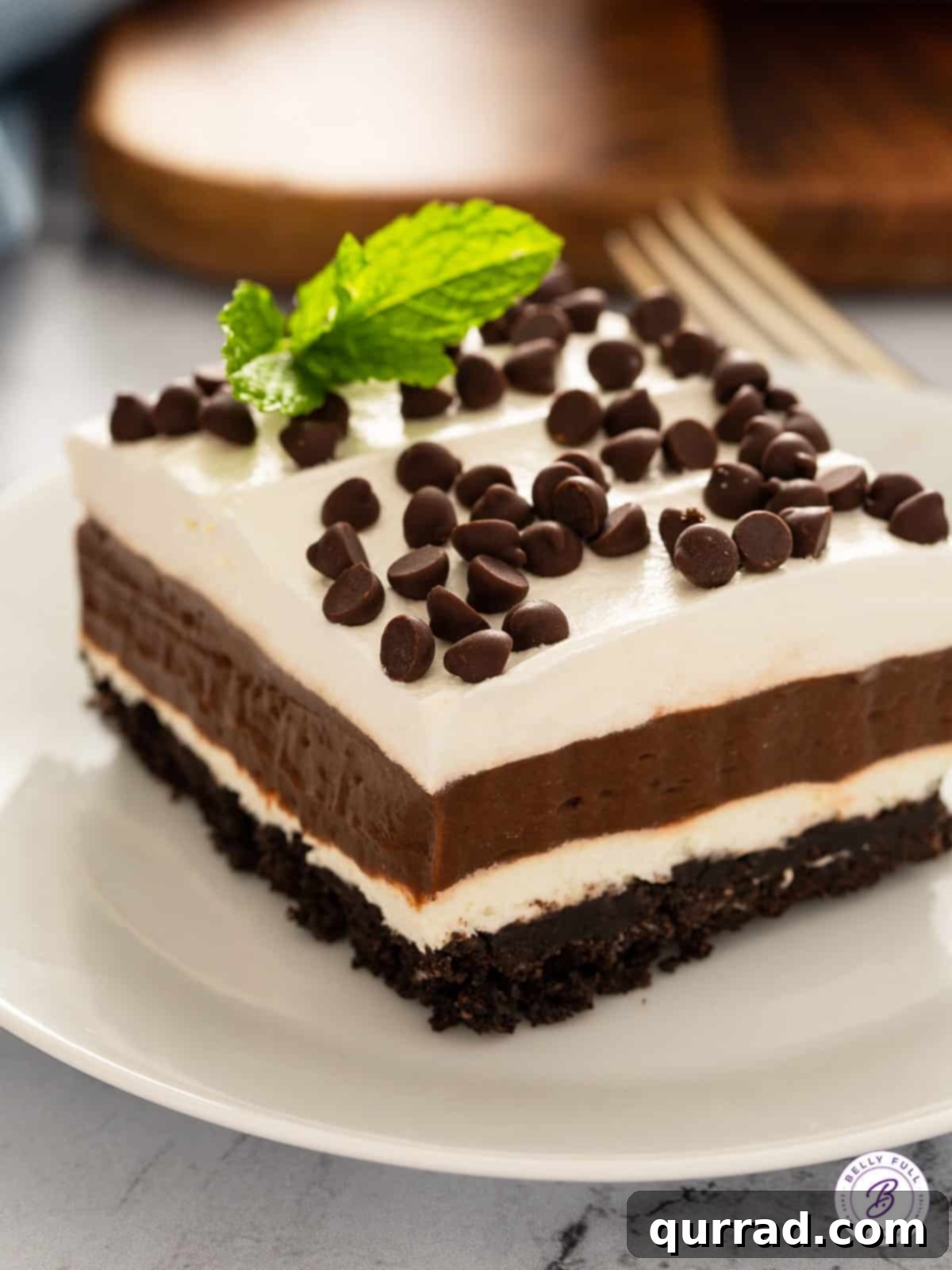 A generous square slice of no-bake Chocolate Lasagna, also known as Oreo Lush, served beautifully on a white plate, showcasing its distinct layers.