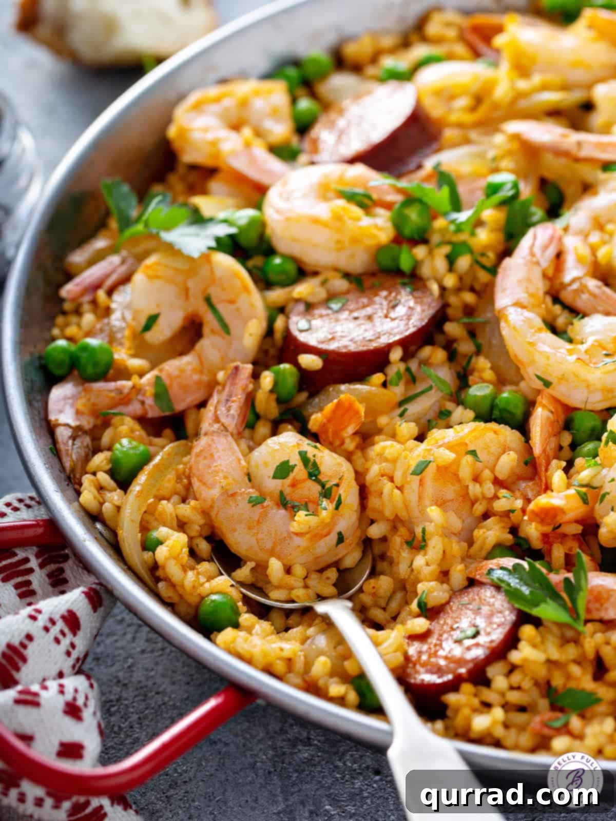 Simplified Weeknight Paella 9 The finished paella dish served directly in the paella pan, generously garnished with fresh parsley and bright lemon wedges.