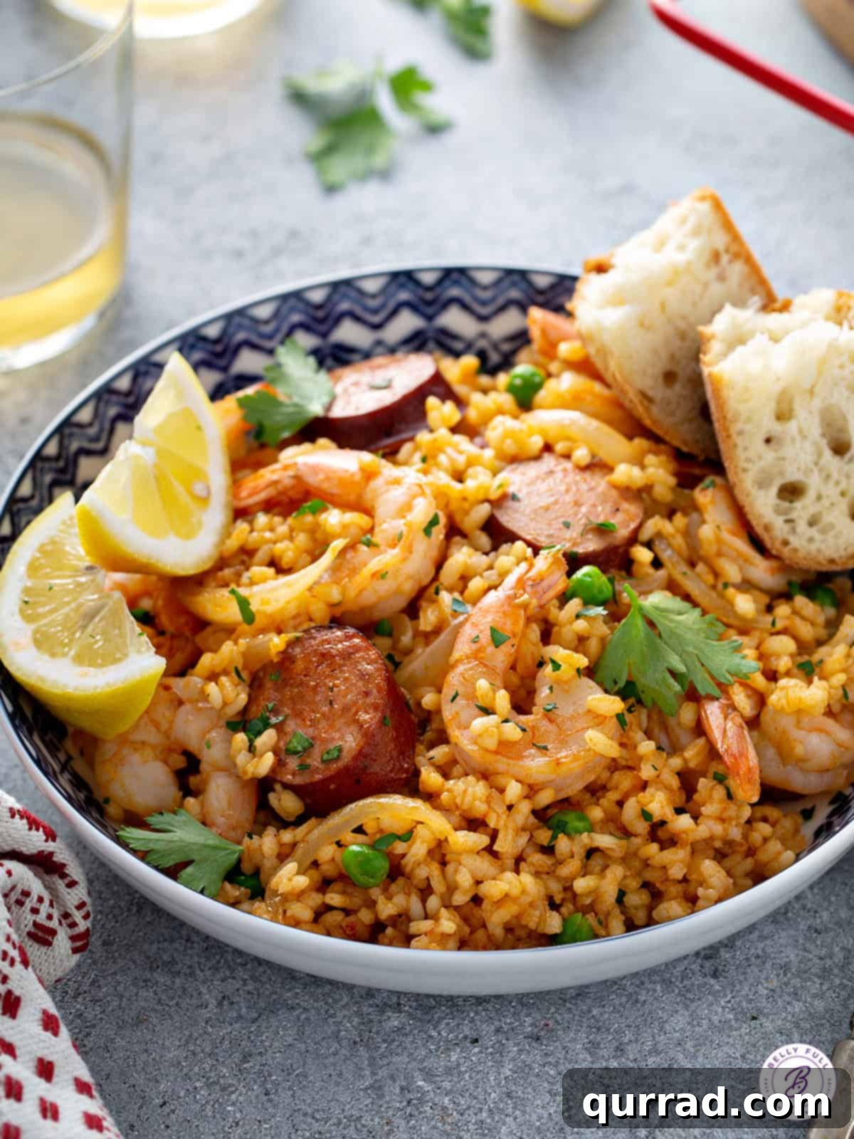 Simplified Weeknight Paella 10 Close-up of a generous serving of shrimp and chorizo paella in a rustic bowl, beautifully garnished with fresh parsley and bright lemon wedges, accompanied by crusty bread.