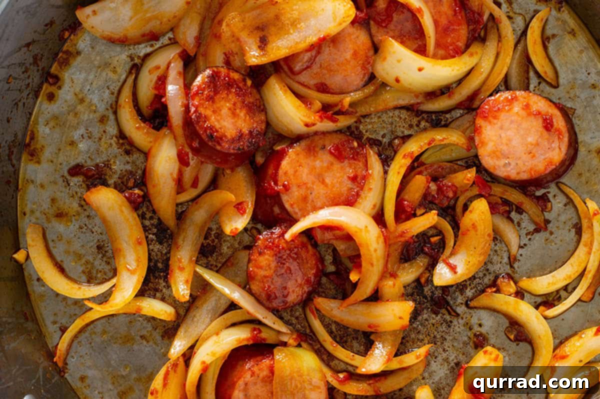 Simplified Weeknight Paella 5 Sliced dried chorizo and onion actively sautéing in olive oil within a large, wide skillet, releasing their aromas.