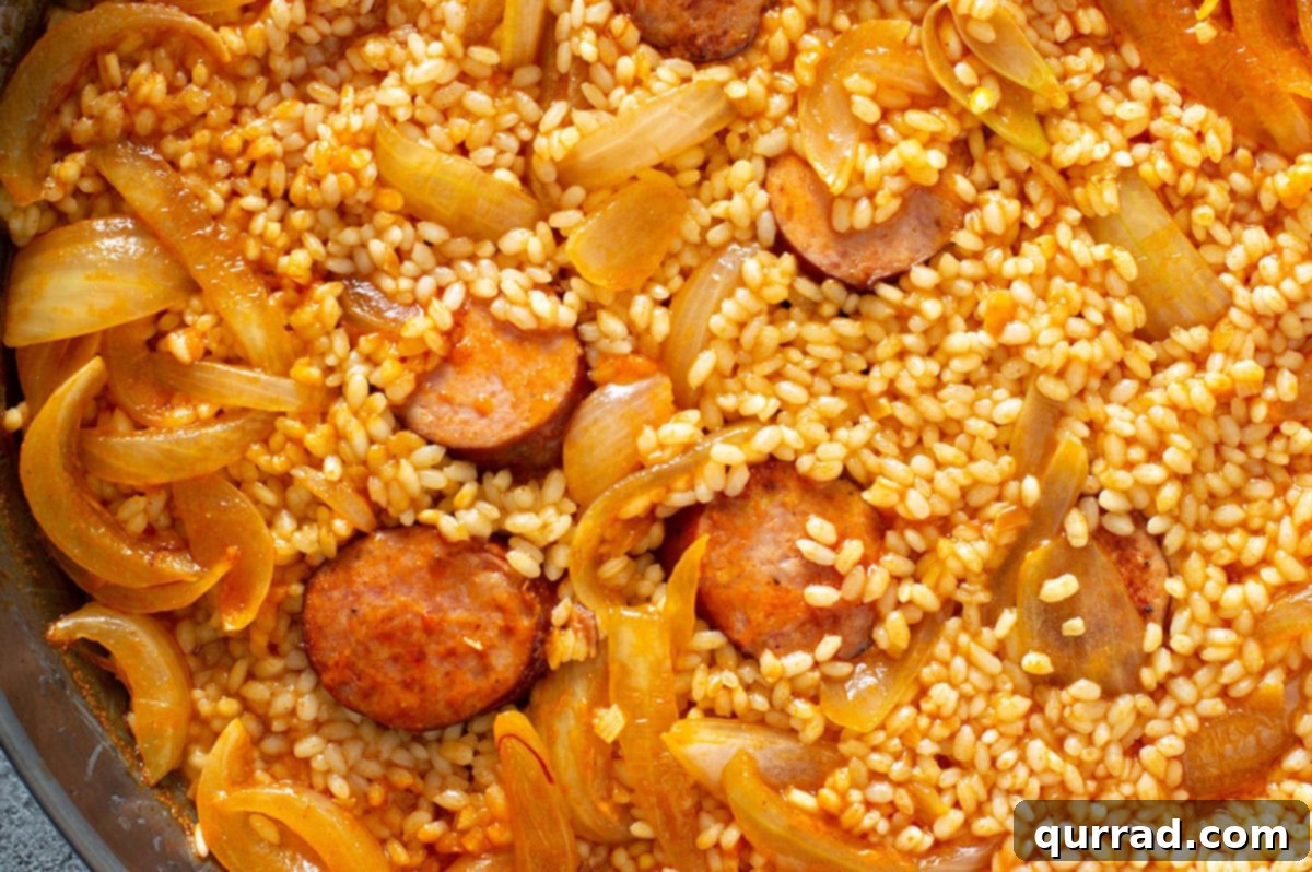 Simplified Weeknight Paella 6 Tomato paste and various spices, including paprika and saffron, being thoroughly stirred into the savory chorizo and onion mixture in the paella pan.