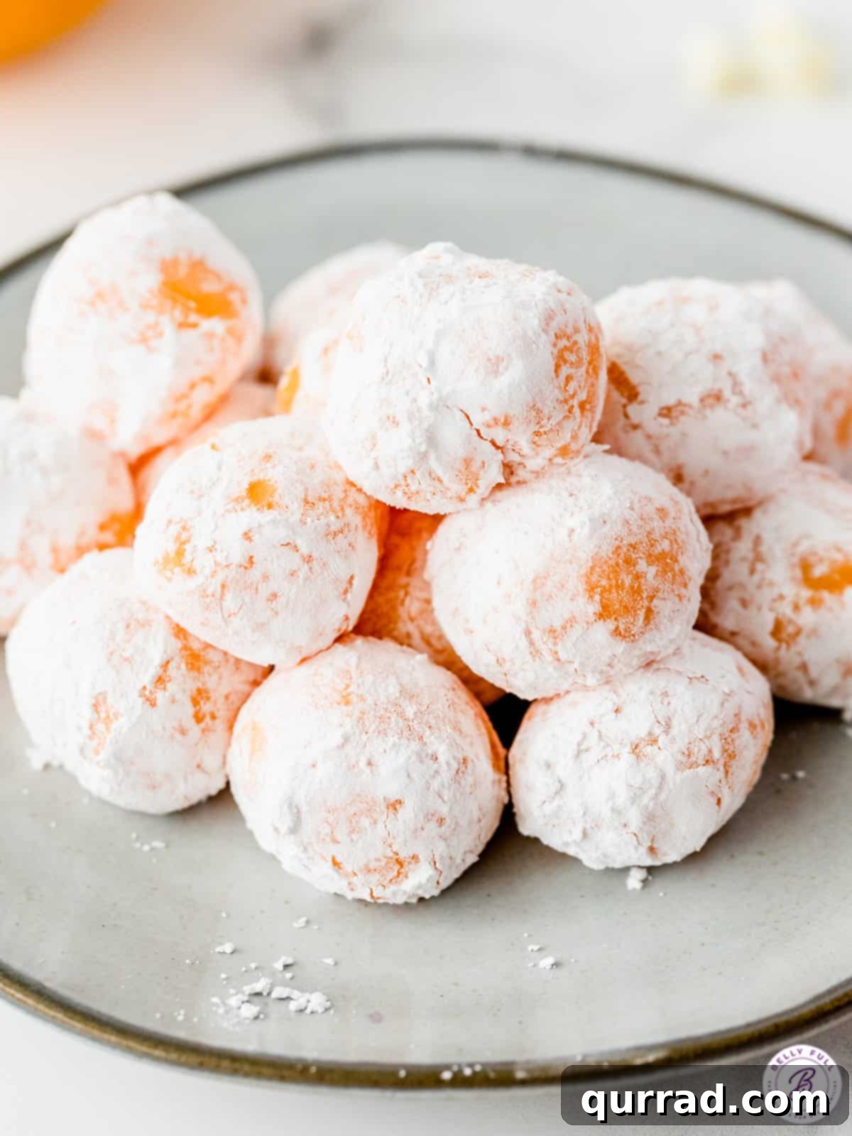 Luscious Orange Creamsicle Truffles 2 stack of chocolate orange creamsicle truffles coated in powdered sugar on silver plate