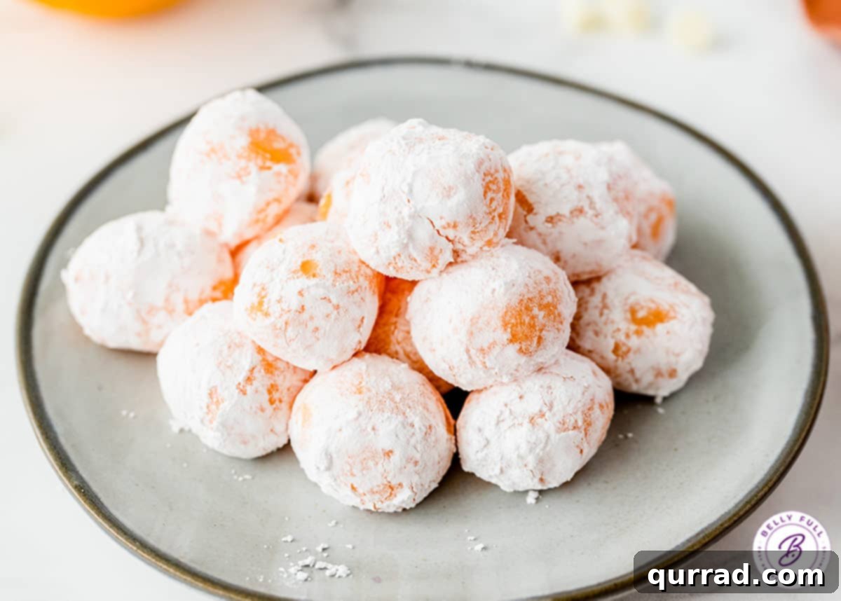 Luscious Orange Creamsicle Truffles 3 mound of powdered sugar coated orange chocolate truffles on plate