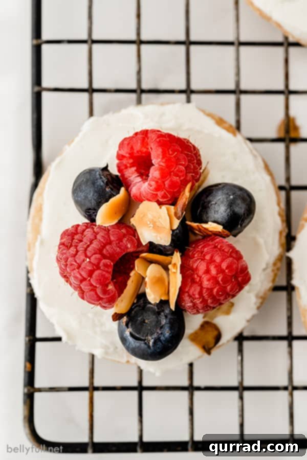 Close-up overhead shot of a single mini fruit tart on a cooling rack, highlighting the rich cream cheese and fresh berries.
