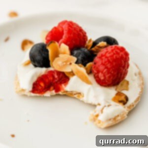 Close-up of a mini raspberry and blueberry fruit tart with a bite taken, ready to be enjoyed.