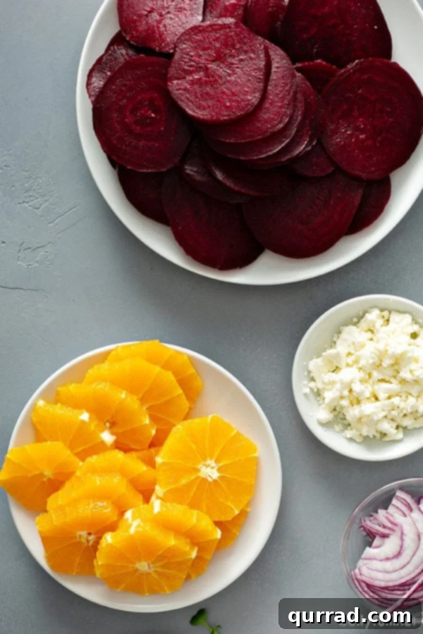 Close-up of neatly arranged sliced oranges, roasted sliced beets, and crumbled feta cheese in white bowls, ready for assembly