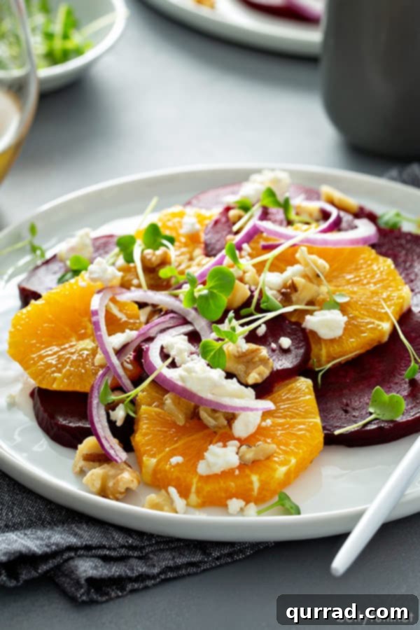 A beautifully composed orange beet salad with vibrant red onion, white feta cheese, and toasted walnuts, served on a pristine white plate