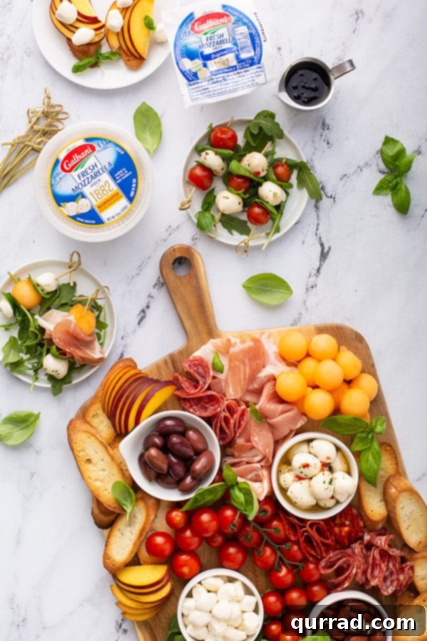 An overhead view of a generously laden meat and cheese board, accompanied by two pristine white plates holding individual caprese skewer appetizers, each perfectly drizzled with balsamic glaze.
