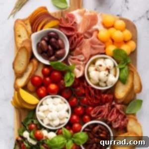 overhead of rectangular meat and cheese board with mozzarella balls, cured meats, fresh peaches, and cherry tomatoes