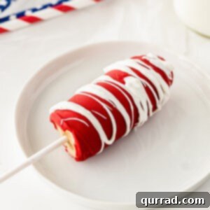 half a frozen banana coated in red chocolate drizzled with white chocolate on a white plate