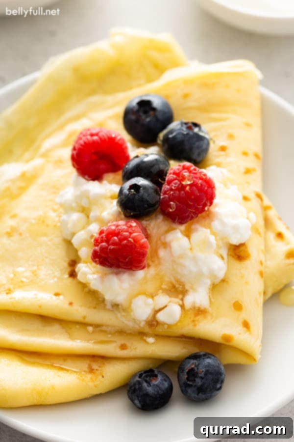 Authentic Russian Blini Recipe 2 Folded Blini with cottage cheese, raspberries, blueberries, and honey