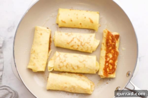 Blintz Bliss 10 Blintzes being pan-fried, with one already flipped to show its golden-brown underside.
