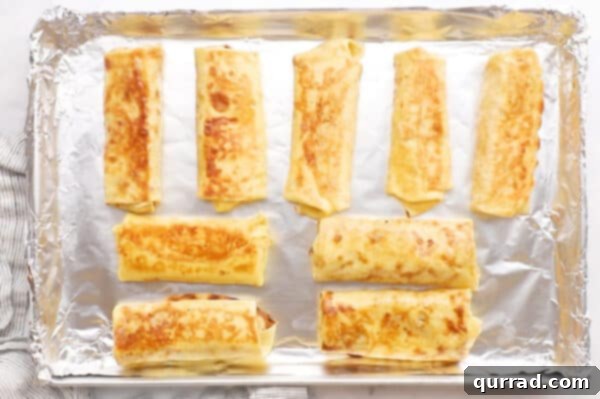 Blintz Bliss 11 Eight cooked blintzes arranged neatly on a parchment-lined baking sheet.
