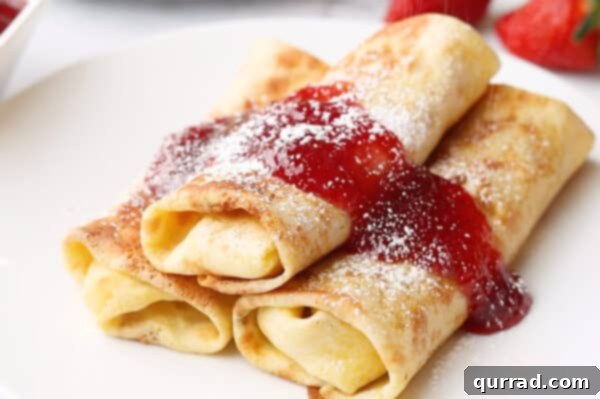 Blintz Bliss 12 Three stacked blintzes on a plate, topped with jam and powdered sugar, ready to be enjoyed.