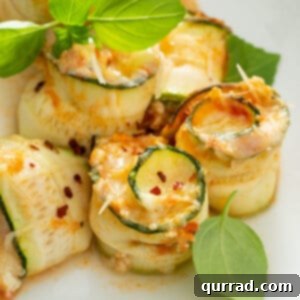 Close up picture of baked zucchini lasagna rolls on white plate with basil leaves