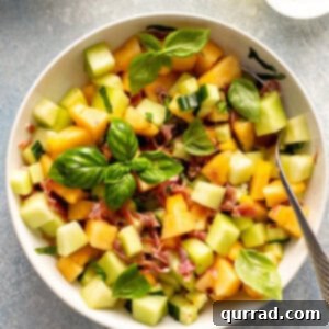overhead Melon Cucumber Salad in white serving bowl with fresh basil leaves