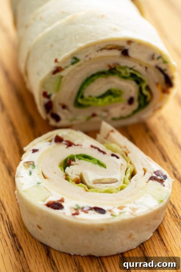 Spiral Chicken Salad Bites 12 A single chicken salad pinwheel appetizer resting on a cutting board, ready to be picked up.