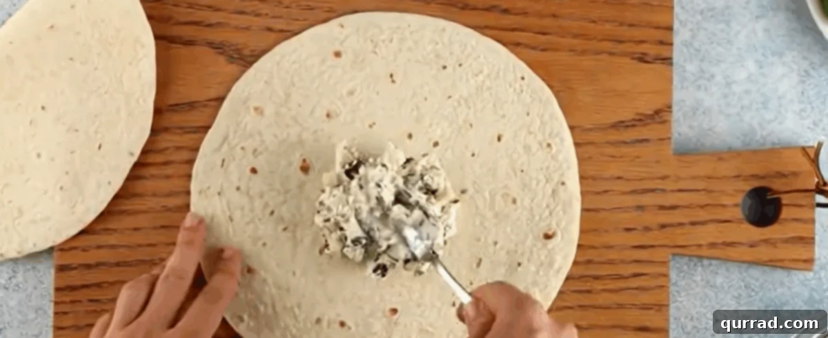 Spiral Chicken Salad Bites 6 Spreading cream cheese mixture evenly over a flour tortilla.