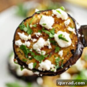 close up slice of grilled eggplant with feta cheese on fork