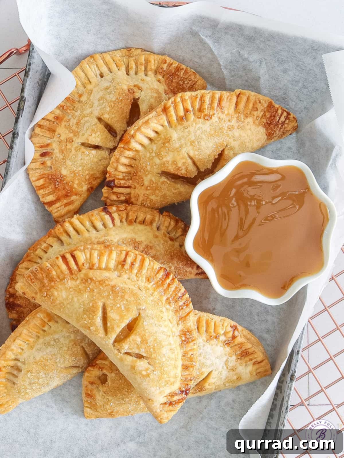 Golden Air Fryer Apple Turnovers 3 overhead basket of triangle hand pies with bowl of caramel sauce