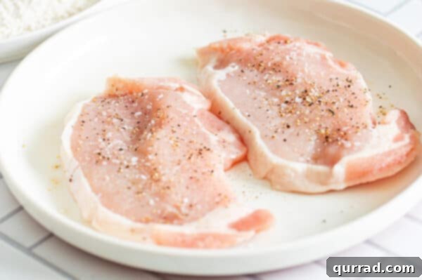 Raw boneless pork chops seasoned with salt and black pepper