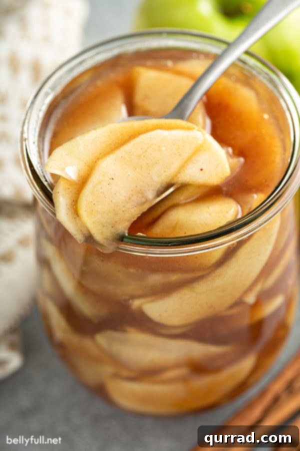 Effortless Homemade Apple Pie Filling 5 portion of apple pie filling on spoon over glass jar