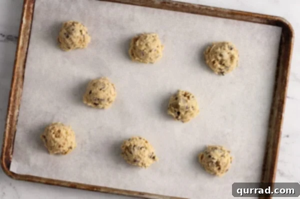balls of chocolate chip cookie dough on parchment lined baking sheet